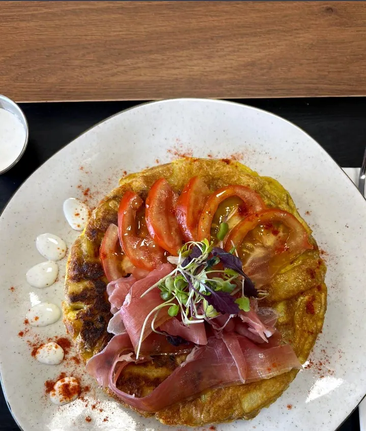 Tortilla de la casa con tomate, jamón y brotes